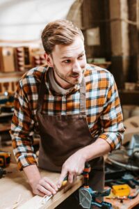 Carpenter Holding Chisel While Carving Wood In Workshop - Carpentry Pros