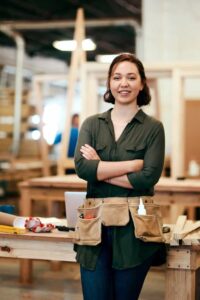 Shot Of A Young Female Carpenter Smiling At The Camera 1 - Carpentry Pros