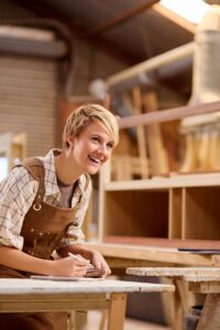 Female Apprentice Working As Carpenter In Furniture Workshop - Carpentry Pros